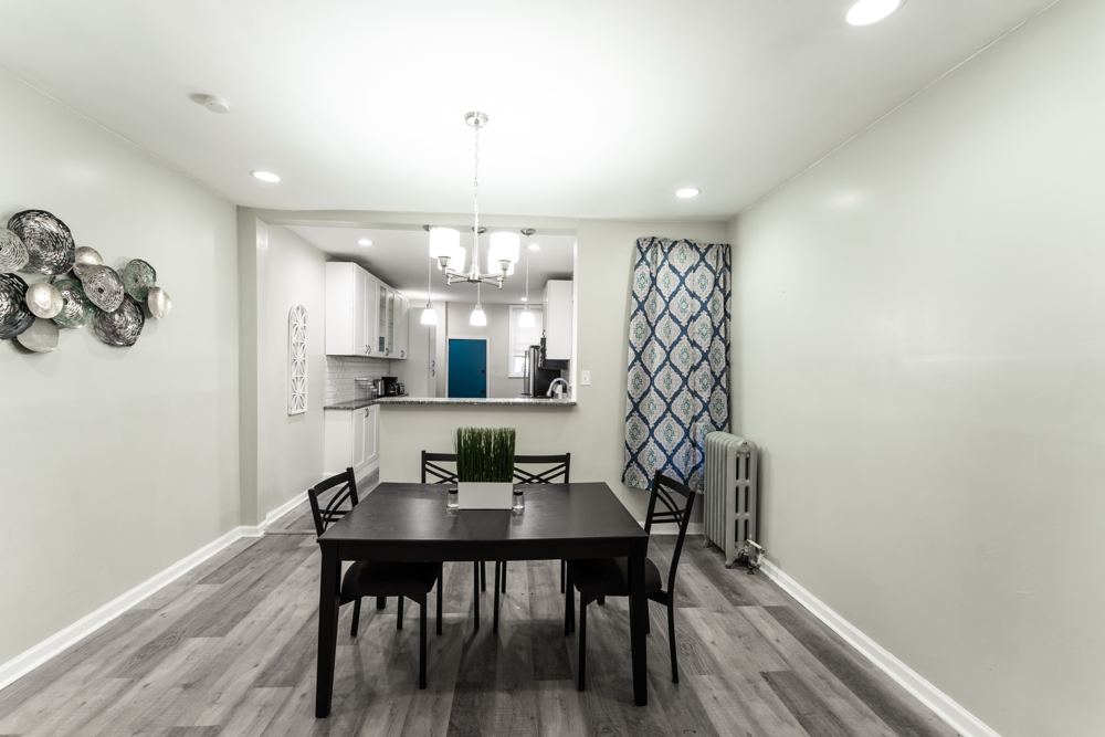 Dining room with a table for four, chandelier and an open kitchen beyond